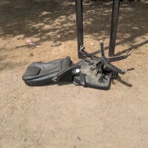 Foto of a broken office chair laying in the sand. The way the chair is broken gives a feeling of a humanized object, the chair looks like it was falling while moving forward.