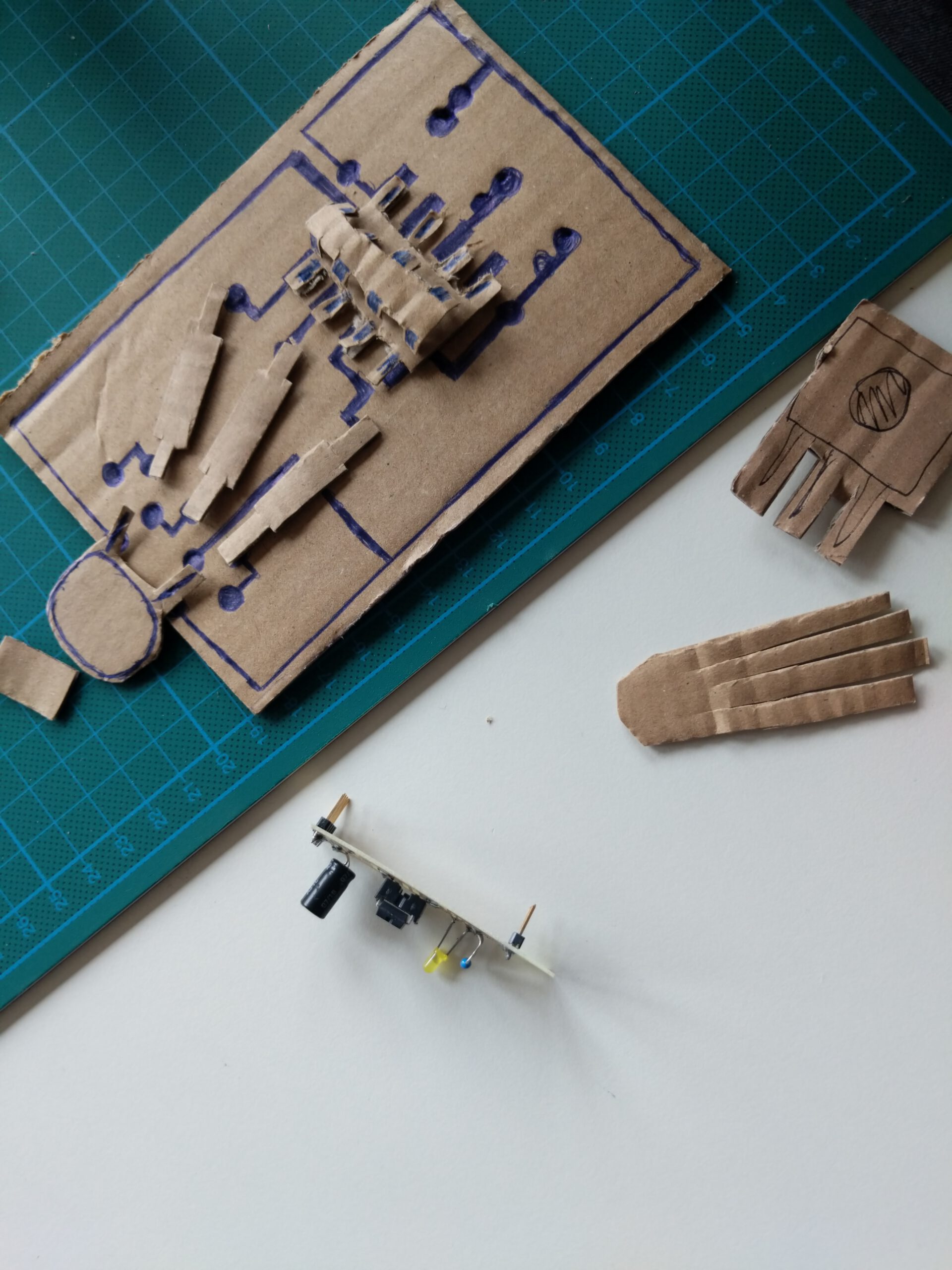 foto showing a paper prototype for a PCB, with several electronic building parts and drawings for the connections